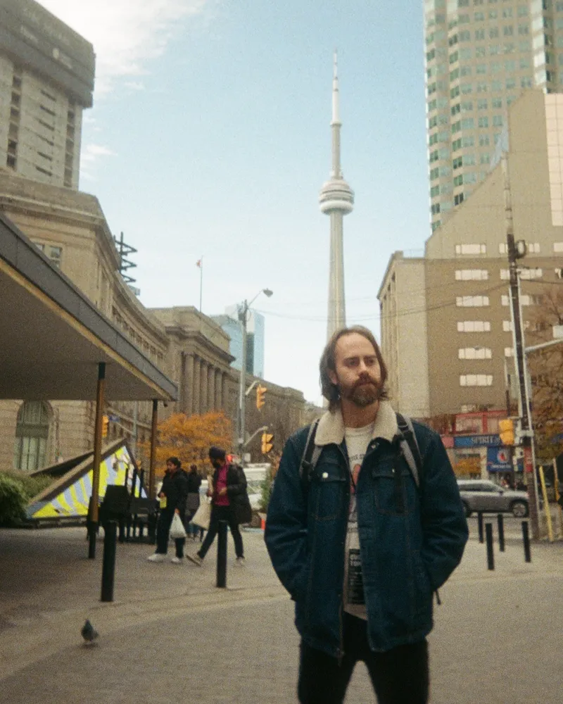 Jordan in a jean jacket on a Toronto street, the CN Tower behind