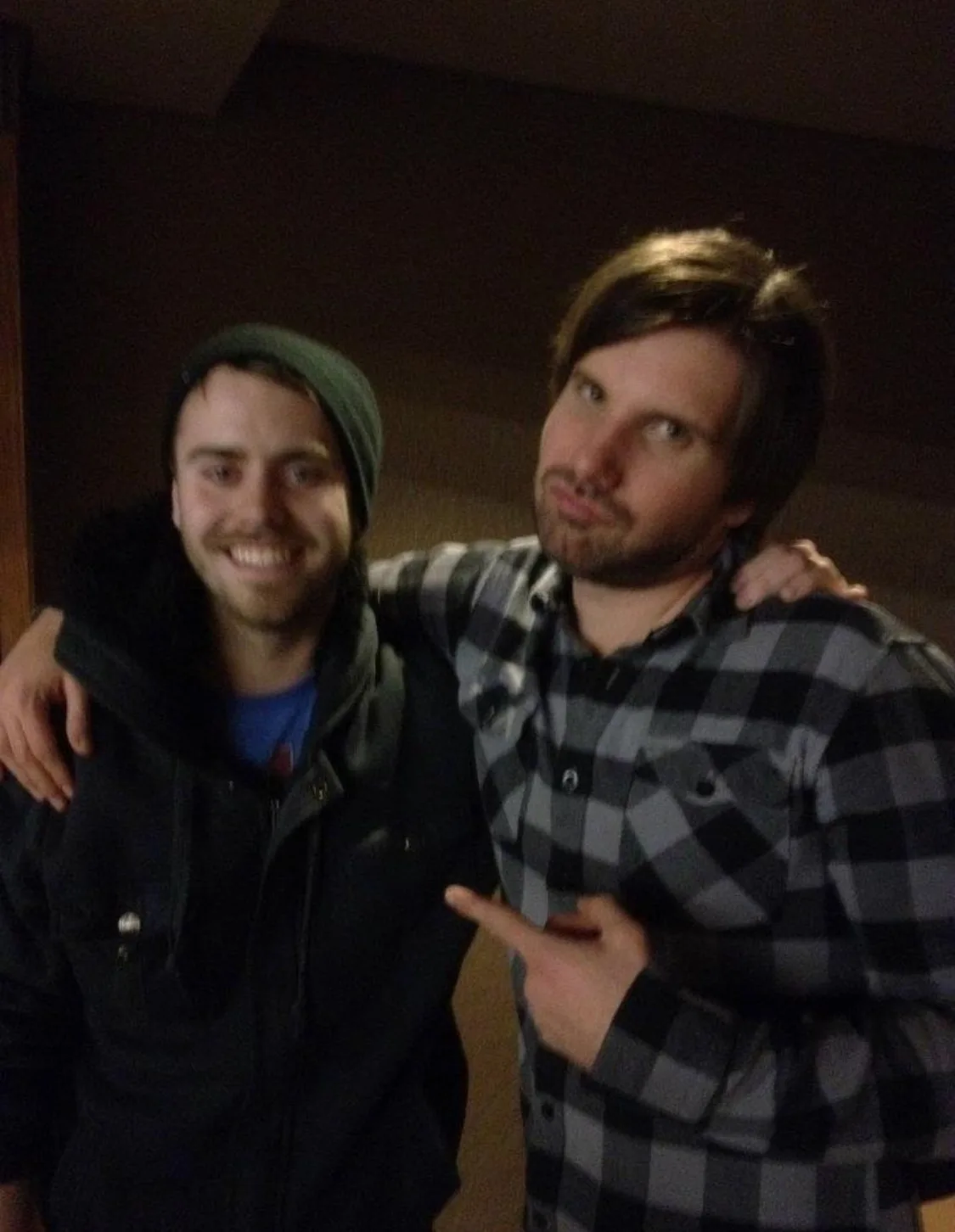 Jordan Clermont in a toque and jacket, grinning, with Jon Lajoie’s arm around his shoulders. Lajoie, in a plaid shirt, is pointing at him.